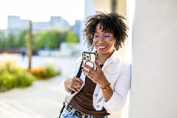 Portrait of a smiling young woman using mobile phone in the city
