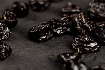 prunes from plums, piled on a board made of stone dried plum fruits, dried fruits on black slate