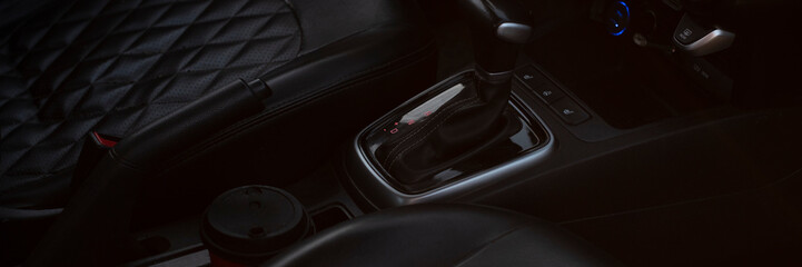 Close-up of a car's interior featuring a gear shift and cup holder. The design is modern with a...