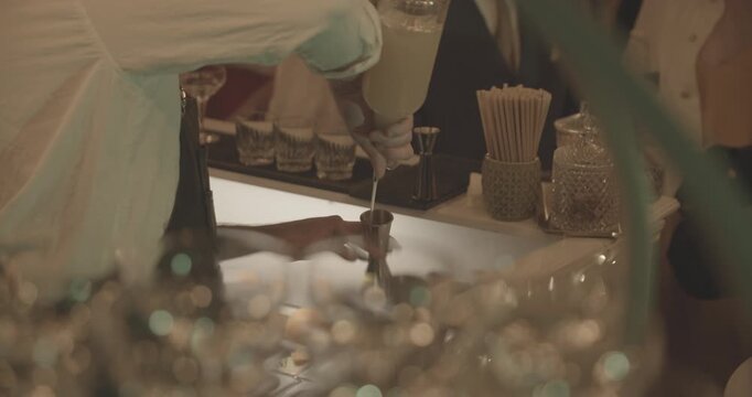 Mixologue versant de l'alcool dans un jigger afin de pr&eacute;rarer un cocktail pour des invit&eacute;s lors d'une soir&eacute;e