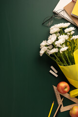 Gift set including white flowers in yellow wrapping, school supplies, and red apples on a...