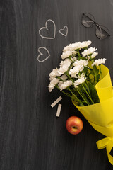 A vertical chalkboard with a bouquet of white flowers, eyeglasses, a chalk-drawn heart, and an...