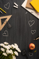 Chalk hearts, stationery supplies, flowers, and an apple arranged on a vertical blackboard inspires...