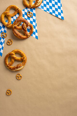 Various vertical freshly baked pretzels on a brown background with festive Bavarian flag patterns,...