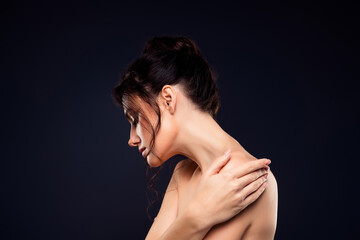 Elegant brunette woman poses gracefully in a studio, highlighting beauty and skincare on a dark...