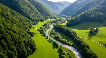 Aerial view of a river winding through a lush green valley with mountains in the background on a sunny day