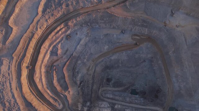 Aerial top view landscape of Open pit mine with big truck, extractive industry for ore and coal at sunrise.
