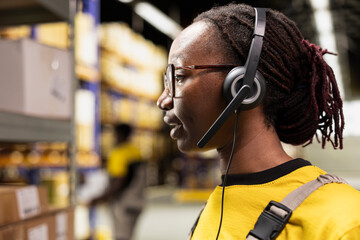 Call center staff member assisting clients in a storehouse depot, checking labels on packages on...