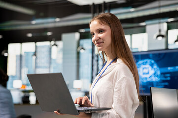 Smiling junior developer utilizing artificial intelligence to optimize performance using laptop....