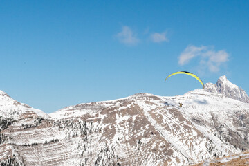 Tandem Paraglider soaring over snow covered Housetop Mountain in Grand Teton National Park from...