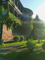 Low-angle view of a historic building with ornate wooden balconies and ivy-covered walls, lit by...