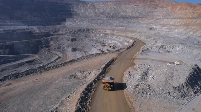 Aerial view mining industry big dump truck transports ore extraction and hauling in open pit mine.
