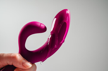 Lube pouring on pink dildo on white background. 