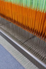 Modern weaving loom macro with warp threads, heddles and reed in textile production