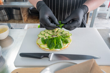 The chef prepares a flatbread with herbs. 