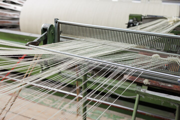 Wool warp threads passing the reed on an industrial weaving loom