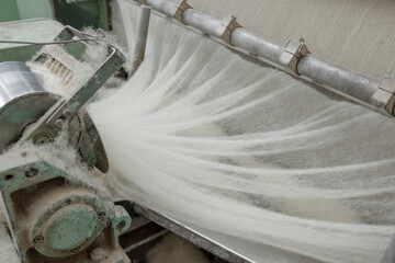 Wool fiber web leaving a carding machine in a textile mill close up