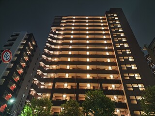 Brightly illuminated apartment buildings in Tokyo at night showcasing urban lifestyle and...