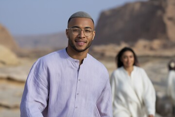 Young african male smiling in desert landscape with female in background