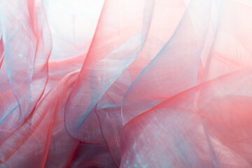  Delicate layers of sheer organza fabric in soft blue and pink tones, gently folded and overlapping, evoking a romantic, dreamy atmosphere perfect for themes of elegance, fashion, and serenity.