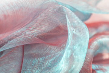 Gentle waves of translucent organza in light blue and pink tones, softly draped to evoke romantic...