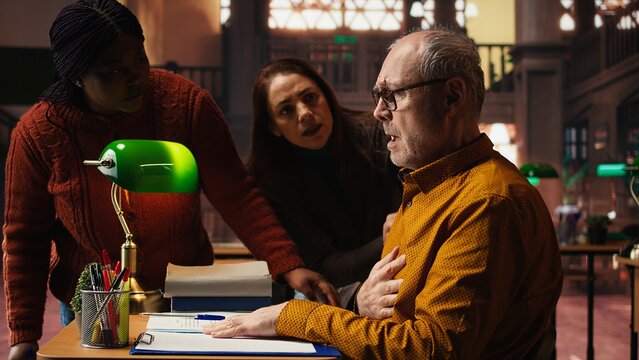 Senior adult in hyperventilation crisis feeling unwell in the campus library, having difficulty breathing and showing vulnerability. Old student having a panic attack emergency.