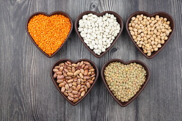 Different type of raw dry legumes composition.   lentils, red lentils, chickpeas and kidney beans. Mix organic legume concept. With Heart shape bowl.
