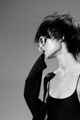 Black and white portrait of a stylish woman with short hair wearing sunglasses and a black top,...