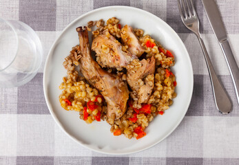 Traditional pearl barley porridge with stewed vegetables and fried rabbit on a plate