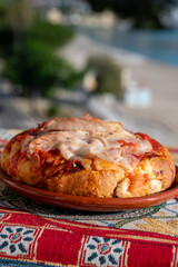 Fresh baked bread, pizza, focaccia or pala romana pizza with tomatoes, vegetables and cheese, street food in Palermo, Sicily, Italy, view on Mondello beach