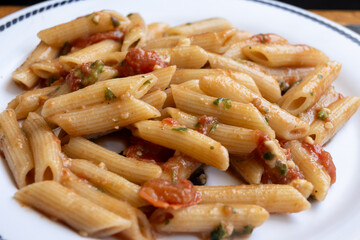Italian everyday food, cooked pasta penne with tomatoes sauce, garlic and parsley