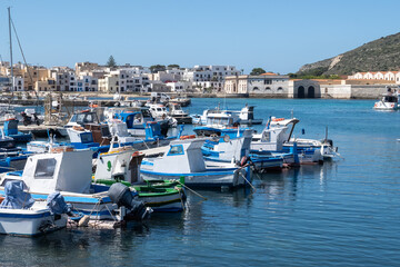 Obraz premium Little traditional colourful fishing boats in Favignana island's harbour, near Sicily, tourists destination, boat trip, Italy