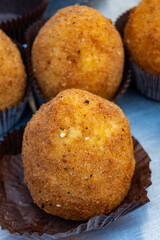 Arancini Sicilian, deep-fried rice balls made with risotto, filled with ingredients mozzarella, ragu, peas, coated in breadcrumbs fried to crispy, brown on market in Palermo, Sicily