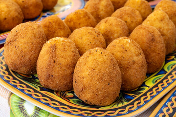 Arancini Sicilian, deep-fried rice balls made with risotto, filled with ingredients mozzarella, ragu, peas, coated in breadcrumbs fried to crispy, brown on market in Palermo, Sicily