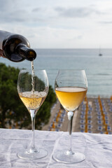 Celebration, birthday party, pouring of sweet muscat white wine from Pantelleria island on holiday on Mondello beach, Palermo, Sicily, Italy