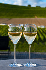Glasses of white sparkling wine brut, grand reserve, champagne on green hilly vineyards in old wine making grand cru Ay-Champagne village in Vallee de la Marne, Champagne, France