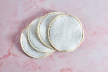 Reusable makeup remover pads resting on pink marble countertop