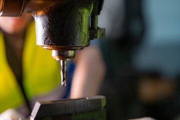 Skilled worker focused on operating machinery in a factory. Wearing high visibility vest and...