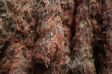 A detailed macro photograph showcasing a dense, tangled texture of raw organic fibers in shades of...