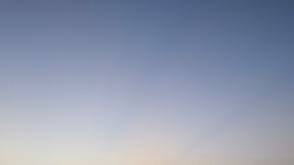A peaceful photo of a blue sky transitioning to a light gray-blue at the bottom. This image is a...