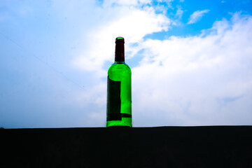Green Glass Bottle Standing Against Blue Sky