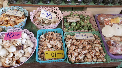 a souvenir counter with various keychains made of natural shells laid out in decorative plastic baskets.  