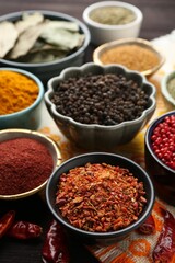 Different aromatic spices on orange tablecloth, closeup