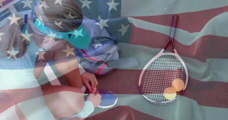 Kneeling tennis player tying shoelaces on tennis court, with racket, balls, backpack, copy space