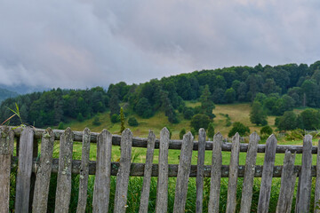 rustic wooden fence frames a lush green hillside