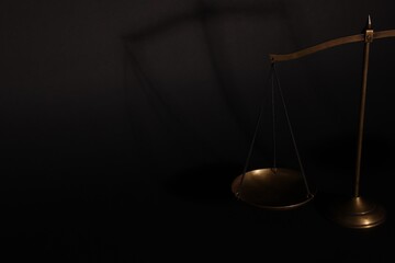 Golden scales of justice on black background, closeup. Space for text