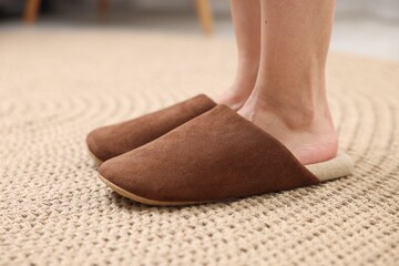 Woman in soft brown slippers on wicker mat, closeup