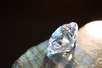 One shiny diamond on stone against black background, macro view
