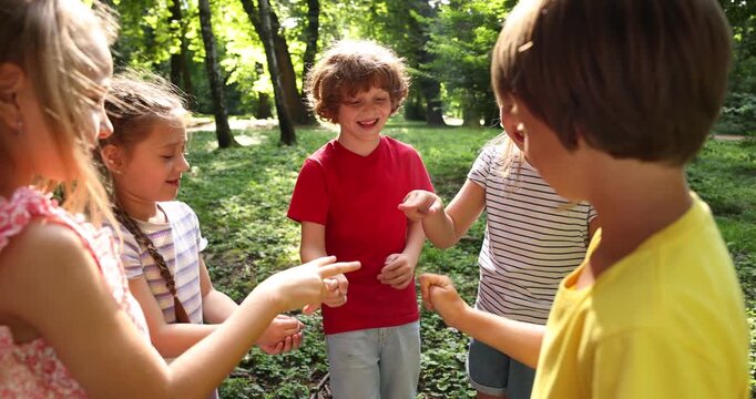 Cute little kids playing rock, paper and scissors in park