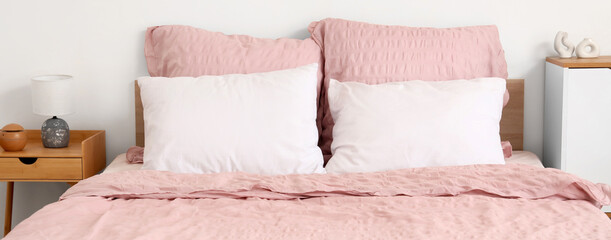 Bed with stylish pink bedding in room